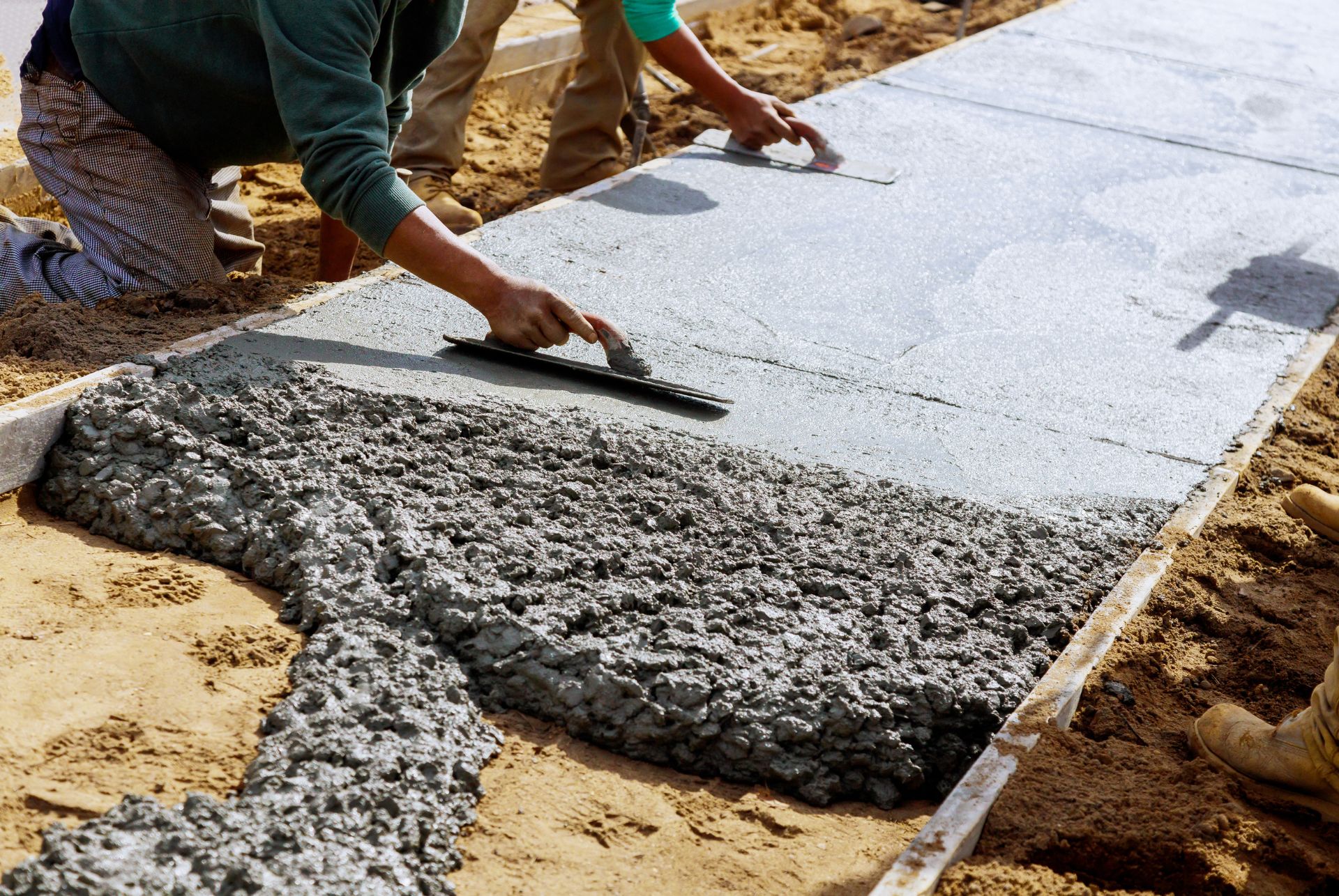a craftman flattening a concrete sidewalk